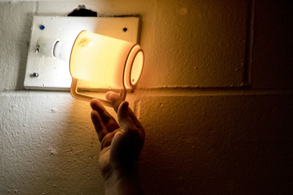 First Place, News Picture Story - Jessica Phelps / Newark Advocate, “Life Locked Up in the County Jail”An inmate at the Coshocton County Justice Center places a plastic cup over a lightbulb in his cell to dim the light, March 4, 2020.